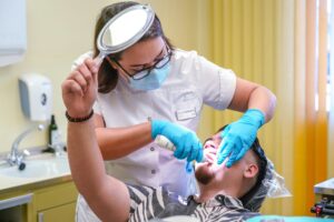 A dentist examining a male patient, representing dental indemnity insurance for hygienists and therapists