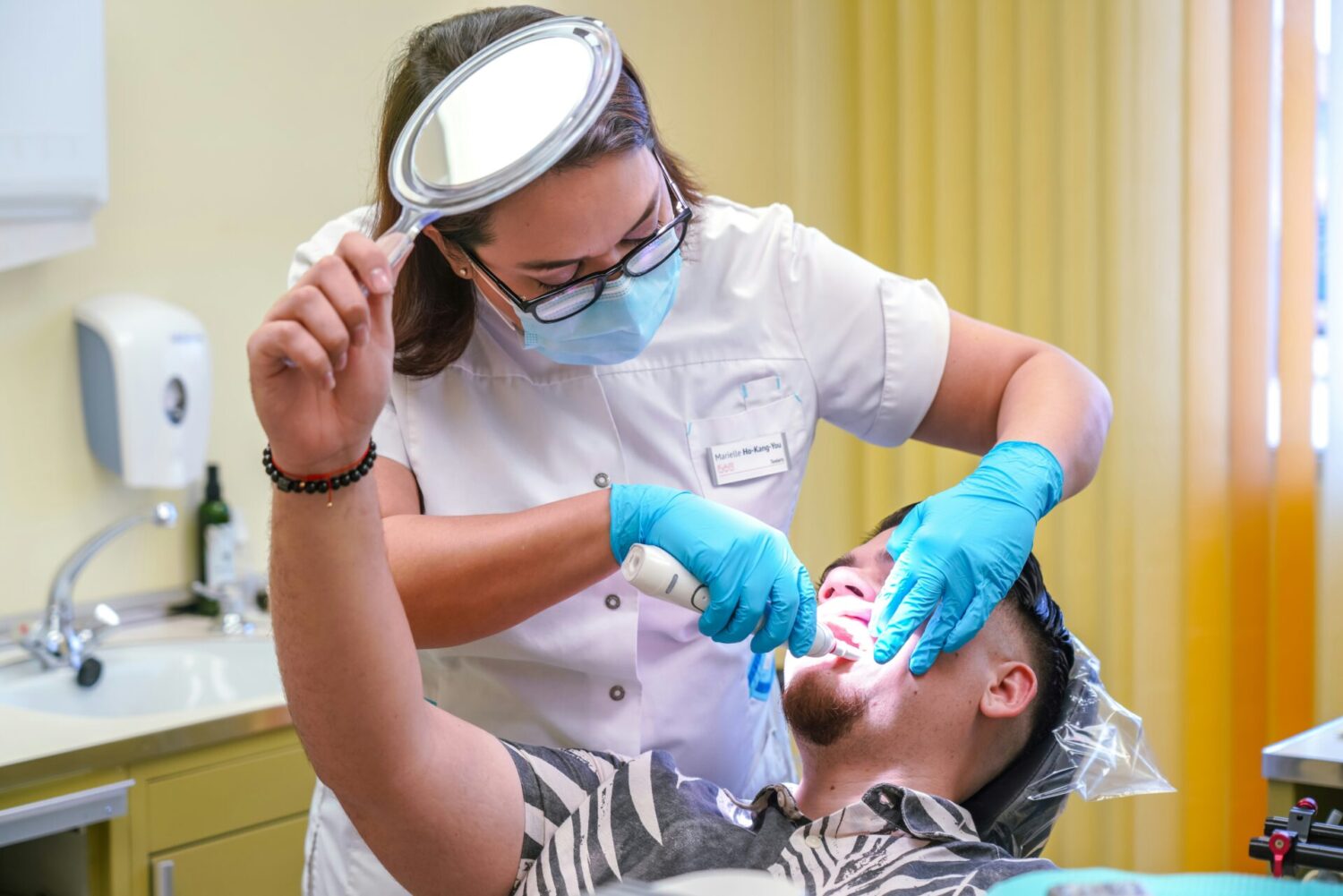A dentist examining a male patient, representing dental indemnity insurance for hygienists and therapists